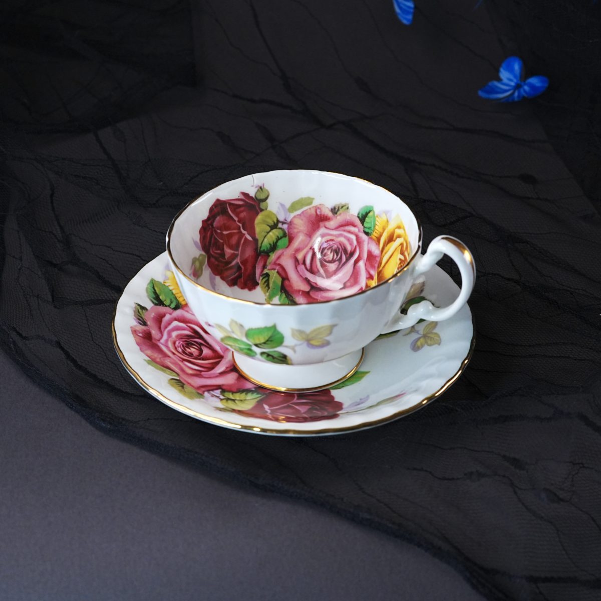 Vintage Aynsley teacup and saucer with large hand-tinted cabbage roses in burgundy, pink and yellow — the kind of hand-colouring done by factory paintresses