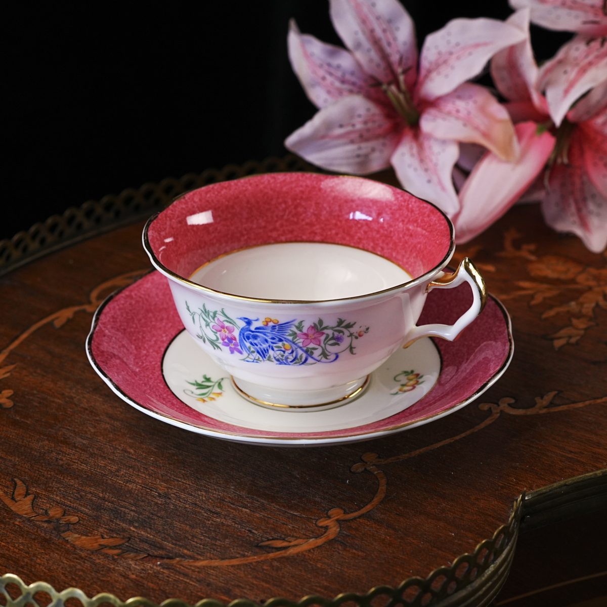 Vintage Coalport Broadway bird of paradise teacup and saucer — a cobalt long-tailed bird among pink blossoms and berries, on a rose-pink sponged border with gilt handle