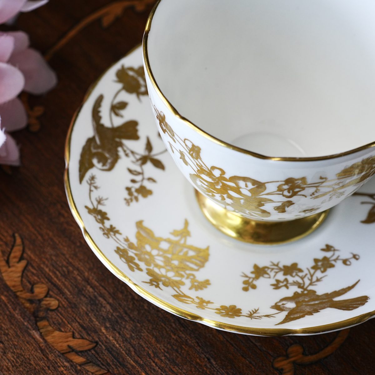 Detail of the Coalport gold bird saucer — golden birds, a small pagoda and flowering branches painted in burnished gold, with a chinoiserie flavour