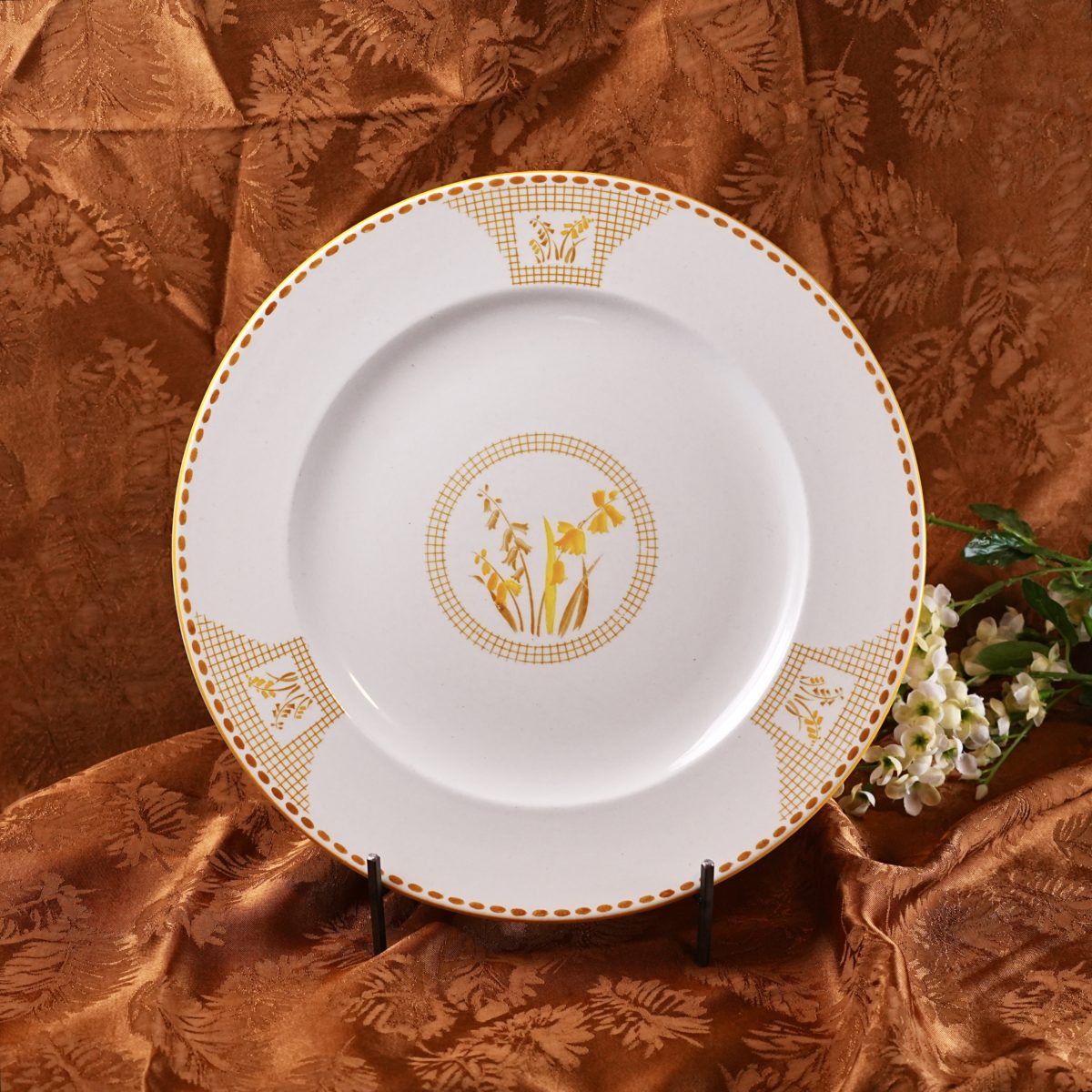A Shelley Art Deco plate with a central geometric gold medallion of stylised wildflowers and trellis-work corner panels