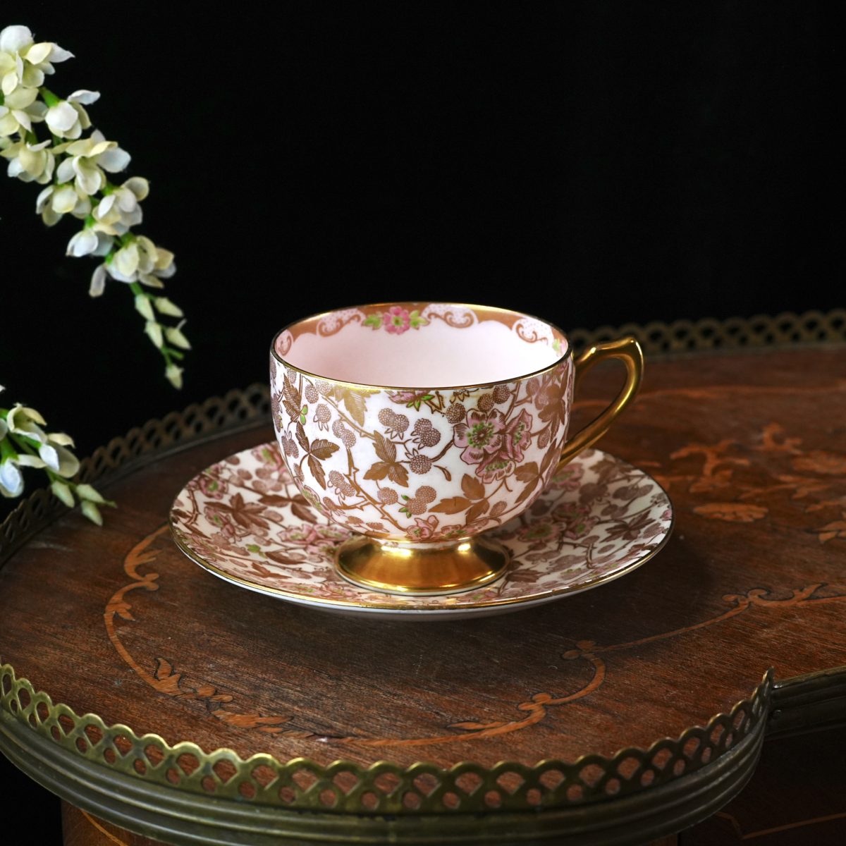 A Shelley Bramble chintz teacup and saucer, an all-over pink-and-gilt brambled floral transfer with a pink interior and gold handle